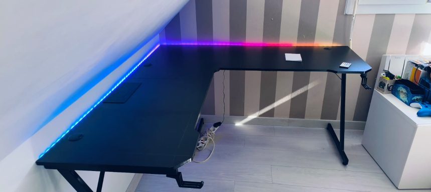 Bureau noir en L avec éclairage LED multicolore sur le bord.
